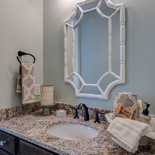 A bathroom with granite counter tops and a mirror, designed and built by a custom home builder based in Carmel, Indiana.