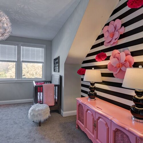 A girl's room with striped walls and pink flowers is a charming and whimsical space. The carefully selected stripes add a playful touch to the room, while the vibrant pink flowers bring a feminine and lively