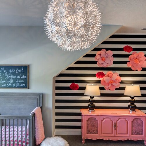 A baby's room with black and white striped walls and a pink crib.
