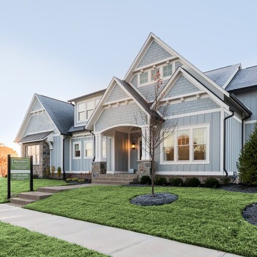 A custom home builder in Carmel, Indiana showcases one of their beautifully designed homes for sale in Westfield. The exterior features a well-maintained lawn with lush grass and an eye-catching
