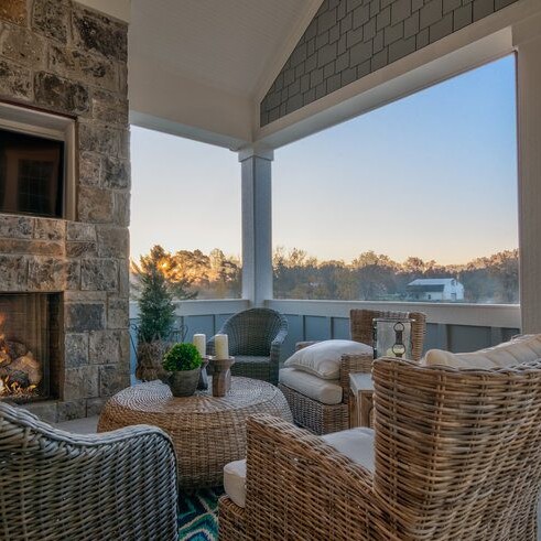 A porch with wicker furniture and a cozy fireplace.
