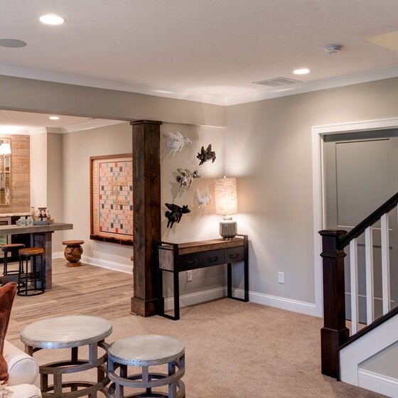 A living room with a staircase and a bar, featuring custom home builder in Carmel Indiana.