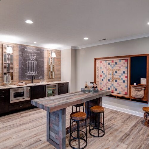 A custom basement bar with stools and a wood floor, perfect for new home construction in Indianapolis or a custom home builder in Carmel, Indiana.