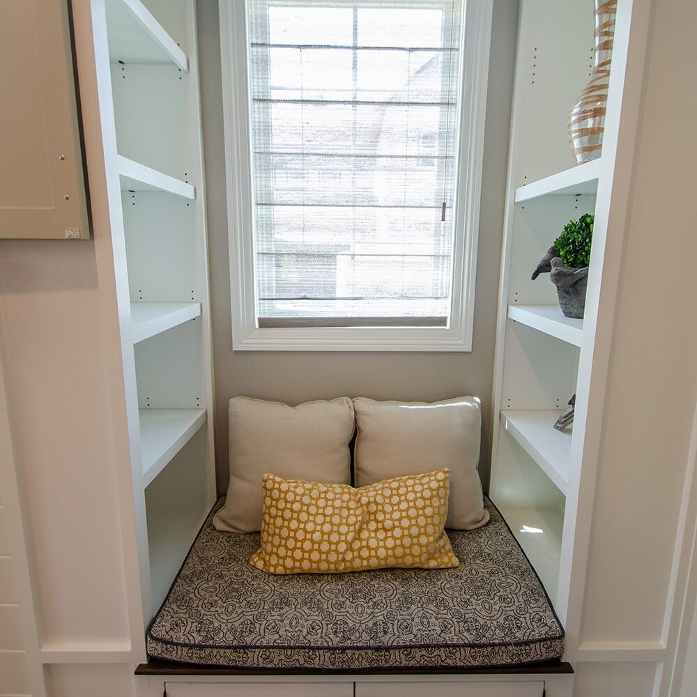 A window seat in a room with white cabinets, designed by a luxury custom home builder.