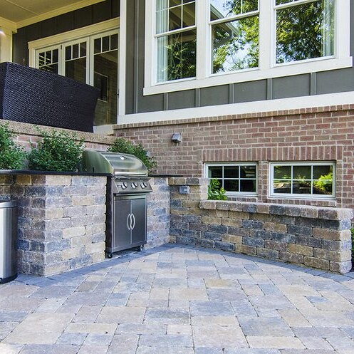 A newly constructed brick patio with a grill and trash can, perfect for enjoying outdoor cooking and entertaining in Carmel, Indiana.