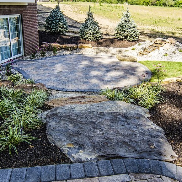 A custom home builder in Carmel, Indiana creates a beautiful backyard oasis with a stone patio and meticulous landscaping. The perfect space for those seeking homes for sale in Westfield, Indiana and the