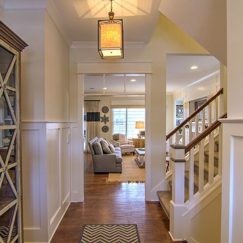 A hallway in a home with hardwood floors and a staircase, designed by a luxury custom home builder.
