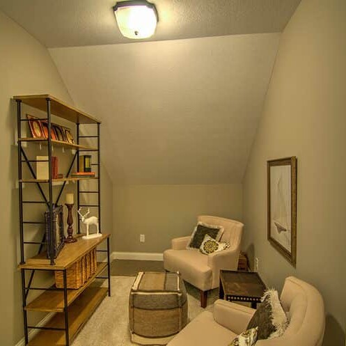 A luxurious room with a chair and a bookshelf, designed by a custom home builder in Carmel Indiana.