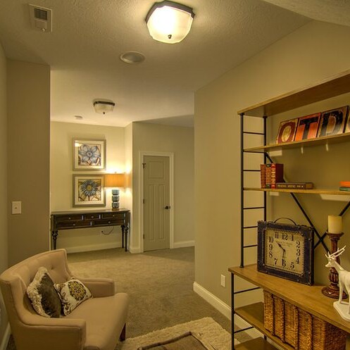 A luxury hallway with bookshelves and a chair, crafted by a custom home builder in Westfield, Indiana.