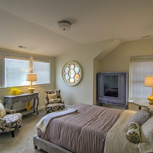 A bedroom with a bed and a chair, built by a Custom Home Builder in Indianapolis Indiana.