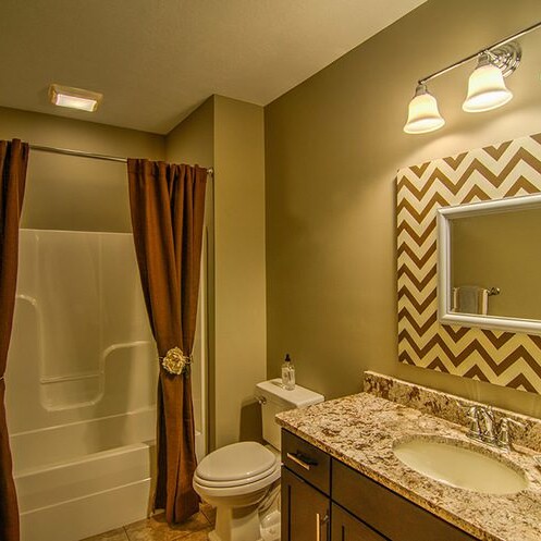 A bathroom with a luxurious brown and beige chevron pattern, designed by a custom home builder in Carmel Indiana.