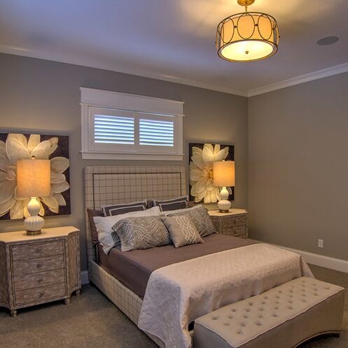 A bedroom with a bed, dresser, and lamp in a Luxury custom home.