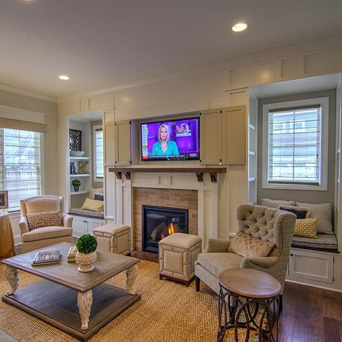 A cozy living room with a fireplace and tv, found in a custom home built by a reputable Custom Home Builder in Carmel Indiana.