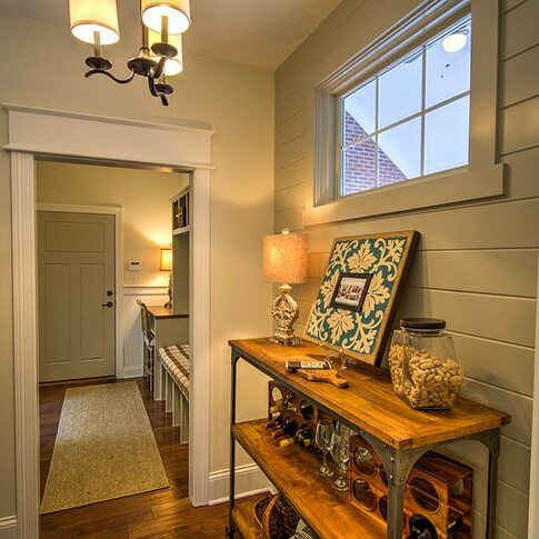 A custom home builder in Carmel Indiana creates a stunning hallway with a wooden shelf and a stylish light fixture.