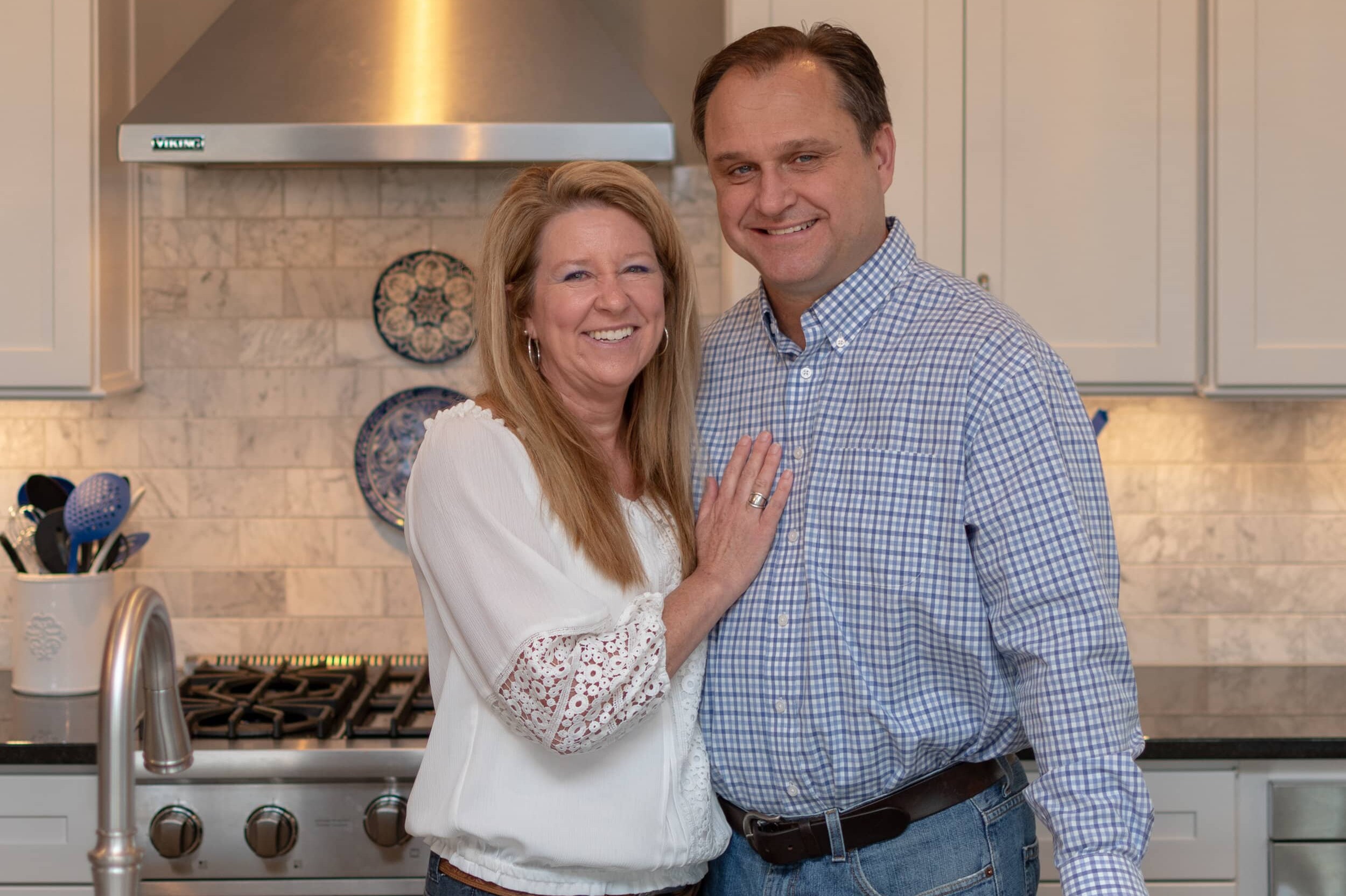 A man and woman posing for a photo in a **new custom home** kitchen.