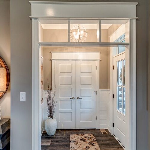 A hallway with a white door and a large mirror in a new home for sale in Carmel Indiana.