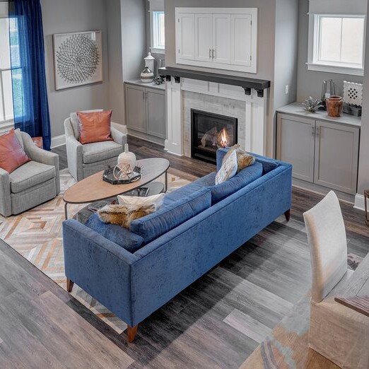 A living room with hardwood floors and a fireplace, designed and constructed by a Custom Home Builder in Carmel Indiana.
