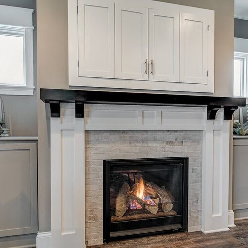 A living room with a fireplace and white cabinets, located in Fishers Indiana.