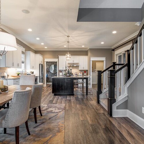 A kitchen and dining room with hardwood floors and a staircase, located in Fishers Indiana.