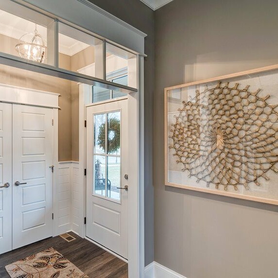 A hallway with a white door and a large art piece. Looking for a Luxury custom home builder in Indianapolis Indiana? Our expert team of architects can create stunning new homes for sale in Carmel