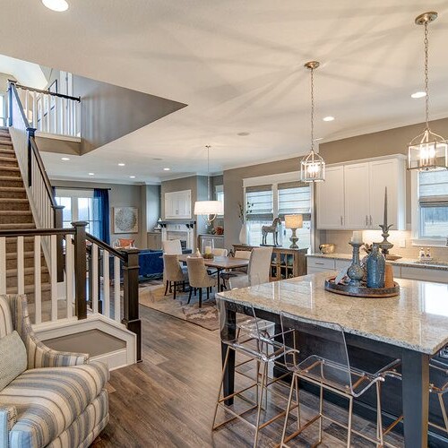 An open floor plan with hardwood floors and a kitchen island, brought to you by the experts in custom home building in Carmel and Fishers Indiana.
