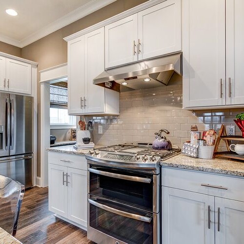 A kitchen with custom white cabinets and stainless steel appliances, designed by a luxury custom home builder in Westfield Indiana.