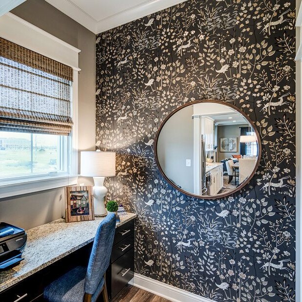 A black and white wallpapered home office with a mirror, designed by a luxury custom home builder in Westfield Indiana.