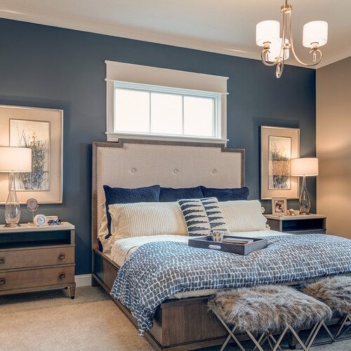 A bedroom with blue walls and a bed, designed by a luxury custom home builder in Westfield Indiana.
