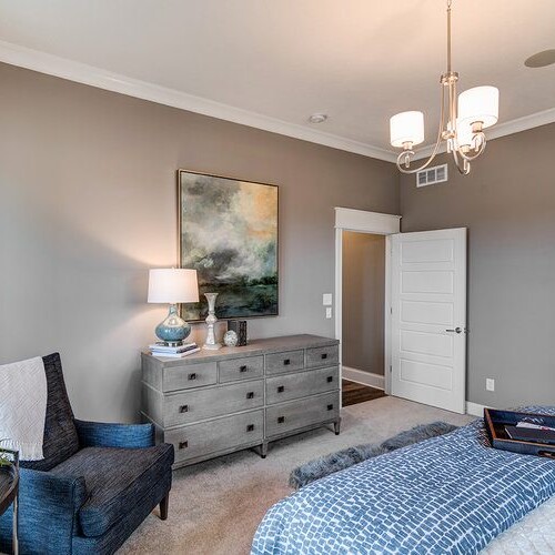 A bedroom with gray walls and a blue comforter in a new home for sale in Carmel Indiana.