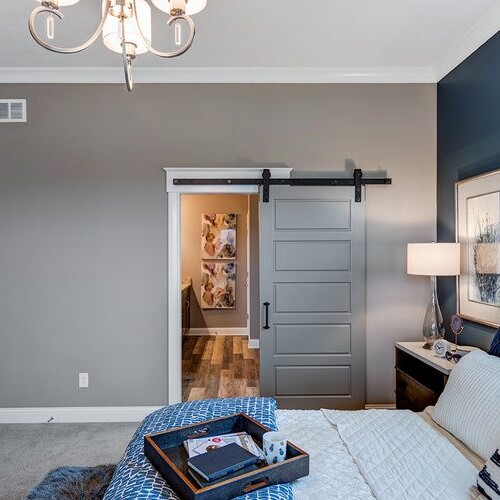 A bedroom with blue walls and a sliding barn door, designed by a Custom Home Builder in Indianapolis Indiana.