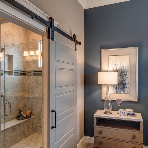 A luxurious bedroom with blue walls and a sliding barn door, crafted by a luxury custom home builder in Westfield, Indiana.