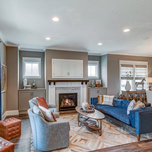 A living room with hardwood floors and a fireplace, built by a custom home builder in Carmel Indiana.