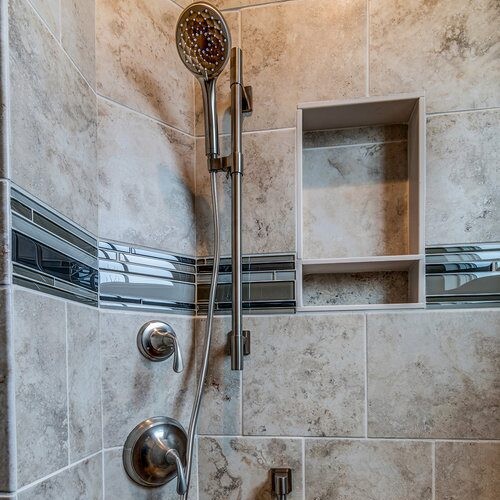 A tiled shower with a hand held shower head in new homes for sale in Carmel Indiana.