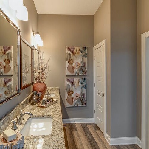 A bathroom with gray walls and wood floors, designed and built by a luxury custom home builder.