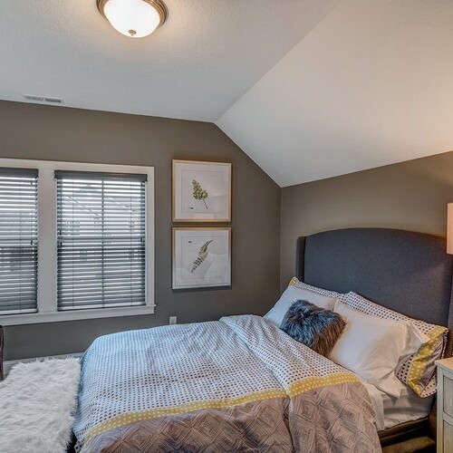 A bedroom with gray walls and a green chair in a new home for sale in Carmel Indiana.