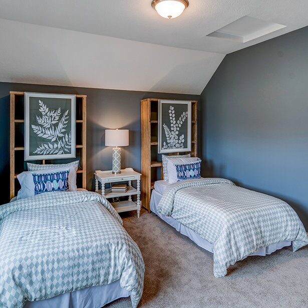 Two twin beds in a bedroom with blue walls. New homes for sale in Carmel Indiana.