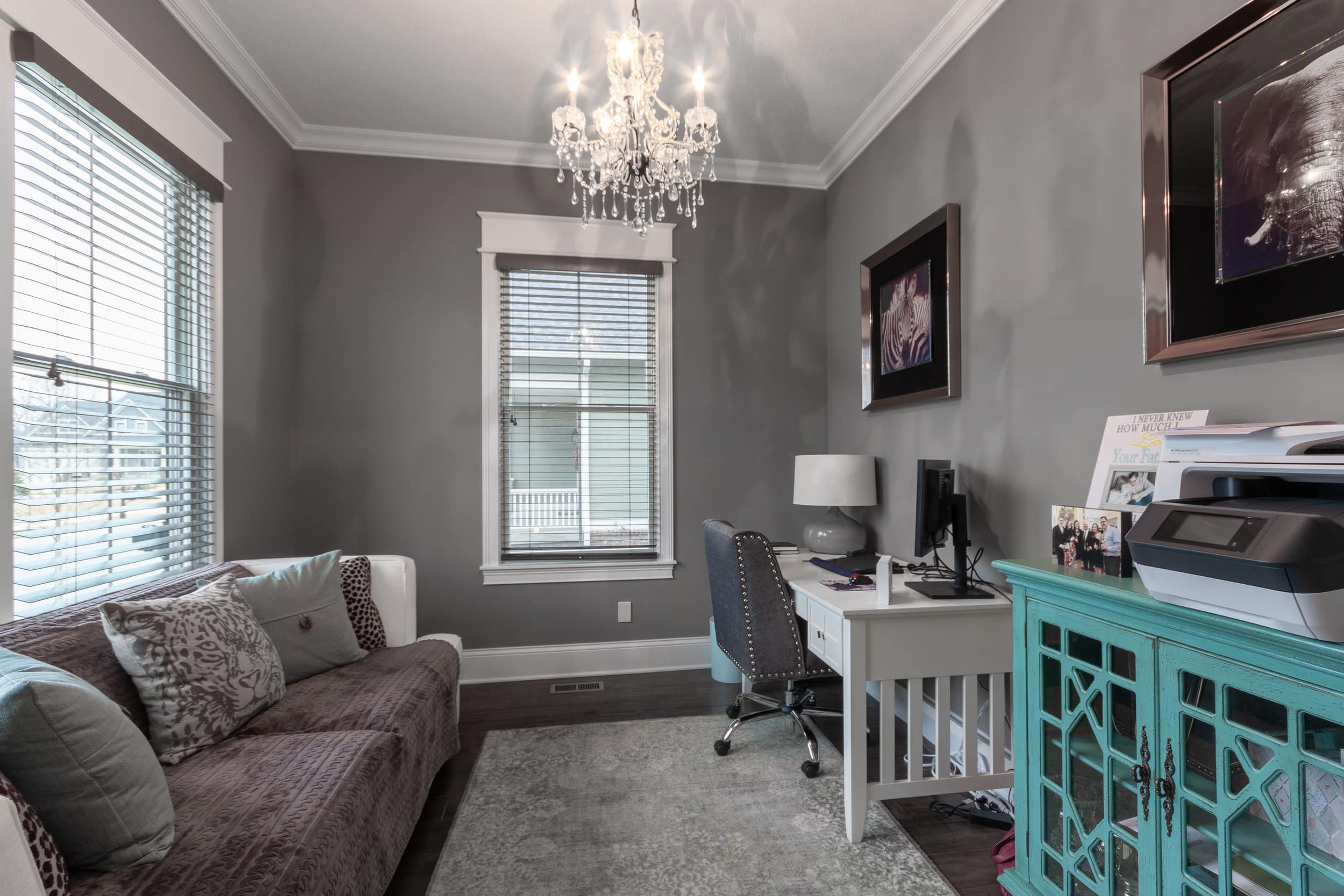 A home office with gray walls and a chandelier designed by a Custom Home Builder Fishers Indiana.