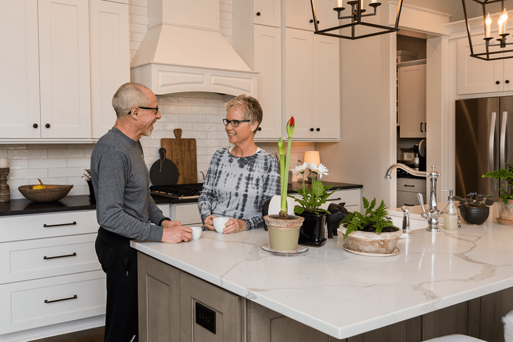 A man and woman standing in a custom kitchen of their new home.