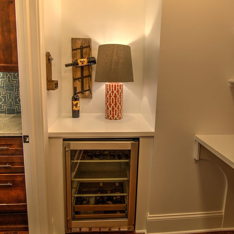 A luxury custom home builder in Westfield Indiana set up a wine cooler in a kitchen illuminated by a lamp.