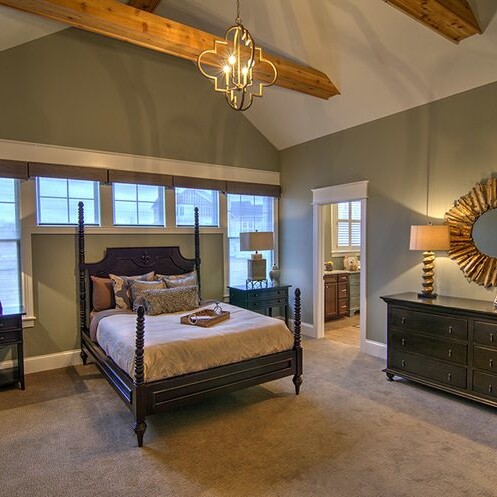 A bedroom with a four poster bed and a dresser, part of new homes for sale in Carmel Indiana by a custom home builder in the area.