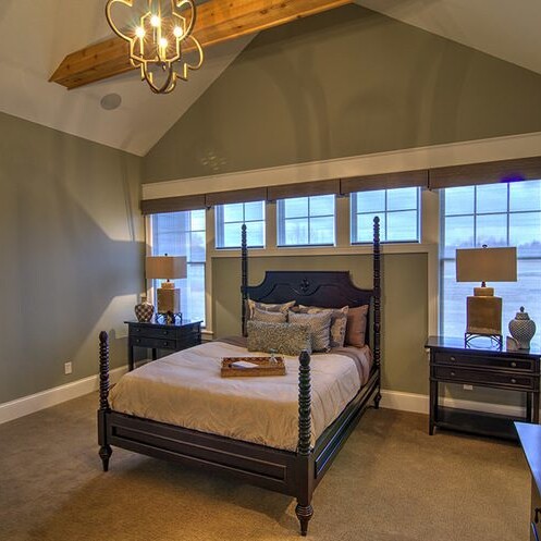 A luxurious bedroom featuring a four poster bed and an exquisite chandelier, crafted by a renowned custom home builder in Indianapolis Indiana.