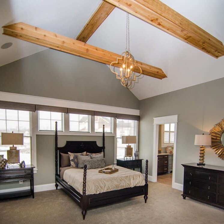 A bedroom with wood beams, a chandelier, and custom-built elements by a reputable Custom Home Builder in Carmel Indiana.