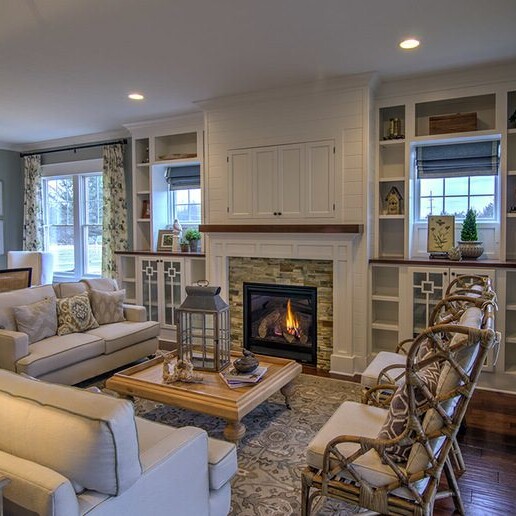 A luxurious living room with white furniture and a cozy fireplace.