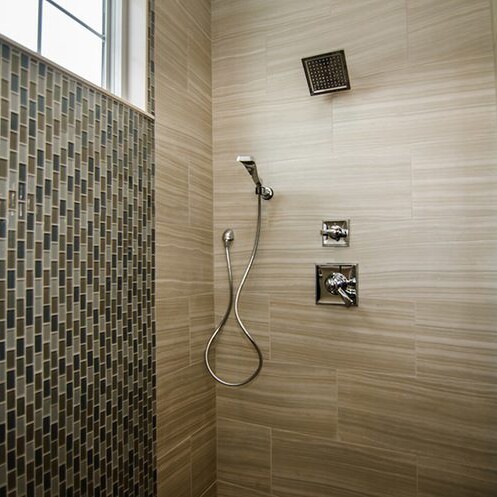 A bathroom with tiled walls and a shower head in a new home for sale in Carmel Indiana.