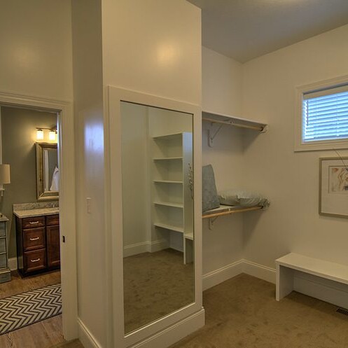 A walk-in closet with a bench and mirror offered by a luxury custom home builder in Westfield, Indiana.