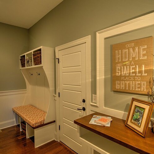 A hallway with a bench and a picture of a custom home.