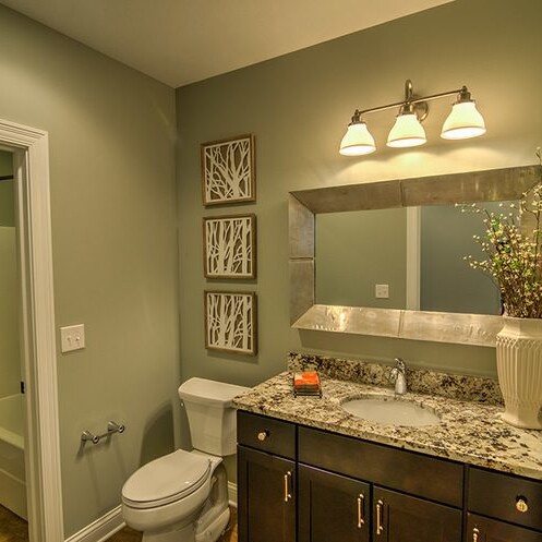 A bathroom with a sink, toilet and mirror designed by a luxury custom home builder in Westfield Indiana.