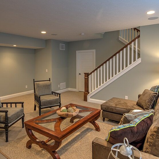 A living room with couches, a coffee table, and a staircase in a custom home built by an Indianapolis Indiana-based builder specializing in new homes for sale in Carmel Indiana.