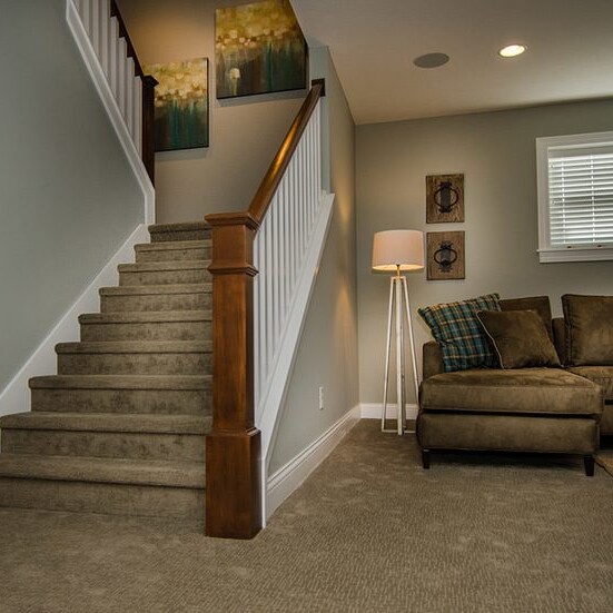 A luxury living room in a custom home with stairs and a couch.