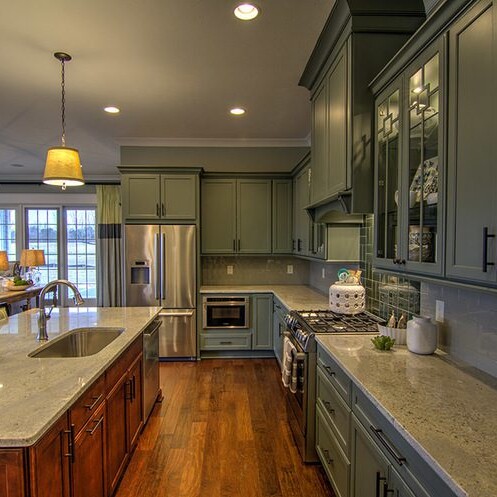 A custom kitchen with green cabinets and a wooden floor, built by a luxury custom home builder in Westfield Indiana.